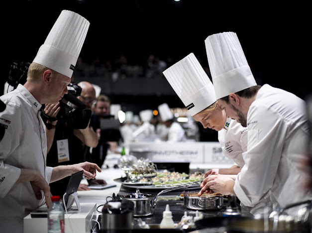 Culinary team working during competition, coach following the plan on a tablet